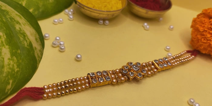 RDS Elegantly Designed Rakhi with a Golden Finish and Shiny Stones and Roli - Chawal